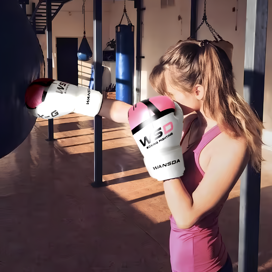 Frau in einem Fitnessstudio, die mit rosa-weißen Boxhandschuhen trainiert, geeignet für Fitness- und Boxtraining.