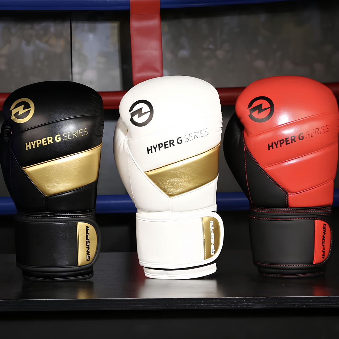 Eine Kollektion von Hyper G Serie Boxhandschuhen in Schwarz, Weiß und Rot mit goldenen Akzenten, ideal für Anfänger und Profis.